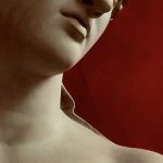 Bibi Campbell - Close up of a Grecian style statue showing part of its face and chest, against a red background.
