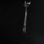 Maddie Cooper - Black and white image of a dimly lit silver spoon.