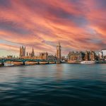 Tom Bailey - View of the Houses of Parliament across the river Thames at sunset with pink clouds in the sky.