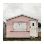 Edward Bailey - Overcast image of a locked up beach hut, sky is moody. Beach hut is pink and white