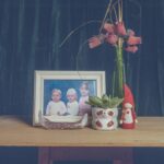 Jasmine Davies - Still life of a old framed family photo, surrounded by a succulent, trinkets, and a vase with roses