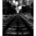 Sam Clarke - Black and white image of a train track going off into the distance, clouds in the sky